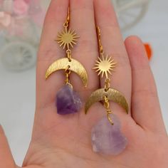 ♡ Raw Amethyst Solar Star Sun Mismatched Earrings ♡ Our Large Crystal Purple Stone Earrings Are A Meaningful And Symbolic Gift. Show Some Well Deserved Love To Yourself And Loved Ones With These Gemstone Earrings. The Elegance Of The Gold Rising Sun Is Gorgeously Complemented By The Beauty The Dangling Purple Crystals. Size: 3.6 inch long, 1 inch wide W H Y ∙ Y O U ' L L ∙ L O V E ∙ I T • They are beautiful dangle earrings that can be worn every day with any outfit • A special piece you will che Celestial Amethyst Gold Jewelry, Handmade Purple Celestial Earrings, Celestial Purple Dangle Earrings, Purple Celestial Dangle Earrings, Purple Crystal Metal Earrings For Gifts, Purple Metal Crystal Earrings As Gift, Purple Metal Crystal Earrings For Gift, Celestial Crystal Pierced Earrings For Gift, Mystical Drop Earrings As Gift