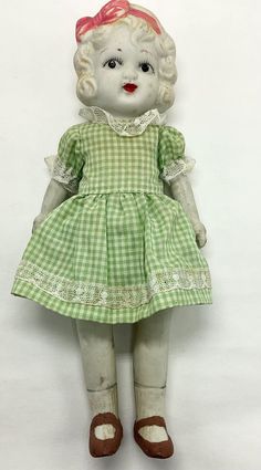 a white and green doll with red hair on it's head wearing a dress