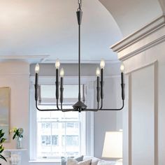 a living room filled with furniture and a chandelier hanging over the couches