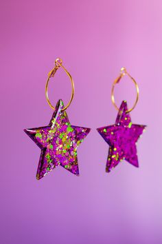 A pair of handmade glittery resin earrings, designed to make you look & feel extra. Playful, eye-catching and vibrant, perfect for festivals, parties, special occasions or just to add a touch of sparkle to your everyday look.  Each pair is meticulously crafted with love and attention to detail, ensuring that you receive a unique piece of jewellery that will make you shine.  A combination of high-quality resin and carefully selected colour-shift glitter creates a mesmerising effect that catches the light and captures attention. Colour shift glitter will first appear as one shade of colour that seems to shift to a different colour depending on the angle you see. ~ SPELLBOUND ~ Star dimensions - w5 x h5cm. 2.5cm gold plated hinged hoops. Designed and hand crafted from my home studio in Bedfor Purple Glitter Party Jewelry, Pink Star Earrings For Party, Pink Star-shaped Party Earrings, Star Shaped Glitter Earrings For Party, Glitter Hoop Earrings Gift, Purple Hoop Earrings For Party, Purple Glitter Earrings For Gift, Hoop Jewelry With Glitter For Gifts, Multicolor Resin Jewelry With Glitter