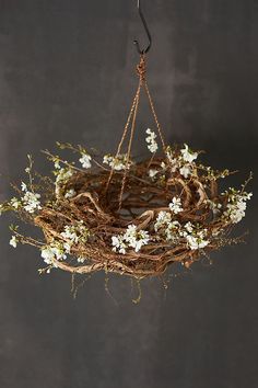 a wreath hanging from the ceiling with white flowers on it and an iron hook in the middle