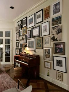 a living room filled with lots of framed pictures on the wall next to a piano