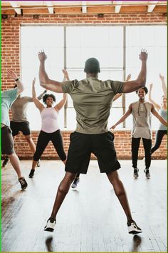 a group of people in a dance class with their arms up and hands out to the side