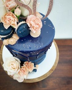 there is a blue cake with flowers on the top and gold numbers on the side