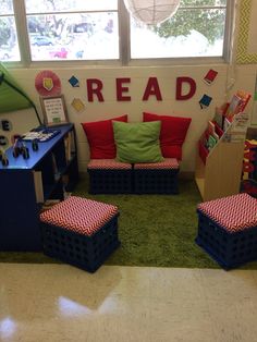 the reading area is decorated with red and green pillows, bookshelves, and blue crates