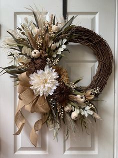 a wreath on the front door with flowers and leaves hanging from it's side