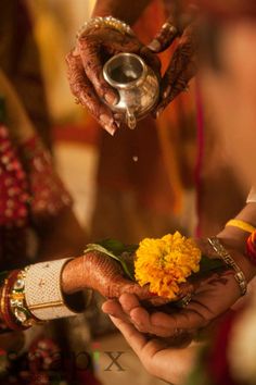 two people holding flowers in their hands while another person is pouring water on the other hand