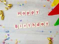 the word happy birthday spelled with scrabbles and confetti on a table