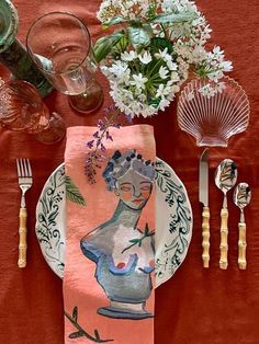 a plate with an image of a woman on it next to silverware and flowers