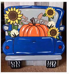 a blue car with sunflowers and a pumpkin in the back