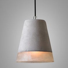 a concrete light hanging from a ceiling fixture with a black cord in front of it