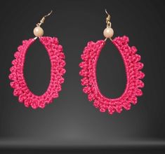 a pair of pink crocheted earrings with pearls