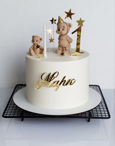 a white cake with gold stars and two teddy bears on top