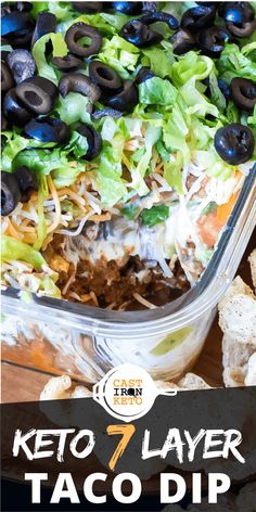 keto 7 layer taco dip with black olives and lettuce in it