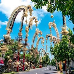 a street lined with lots of tall white and gold decorated archways next to trees