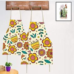 two aprons hanging from hooks in front of a wall with flowers and plants on them