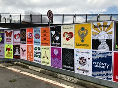 a wall with many different posters on it and a pedestrian bridge over the street in the background
