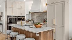 a kitchen with an island and stools in front of the counter top, along with several cabinets