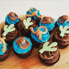 cupcakes with chocolate frosting and fondant decorations on a wooden platter