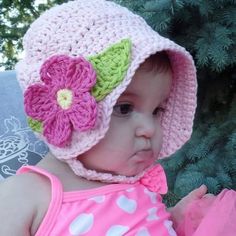 a baby girl wearing a crocheted hat with flowers