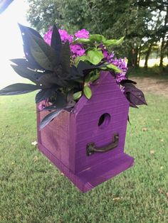 a purple bird house with flowers in it