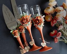 three wine glasses decorated with flowers and hearts are sitting next to a knife on a table