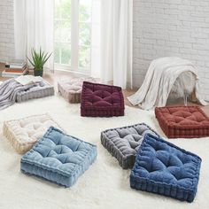 four different colored dog beds on a white rug