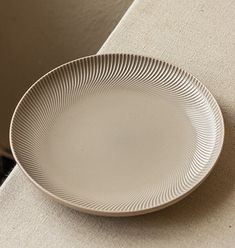 a white plate sitting on top of a table next to a window sill in a room