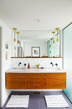 a bathroom with two sinks, mirrors and rugs in front of the sink area