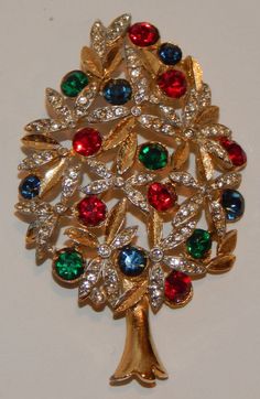 "Every piece of vintage costume jewelry is a book piece. this one included. Made by Sphinx, it has the A1226 number on the back. Three jewel-toned Swarovski rhinestones of ruby red, emerald green and royal blue, decorate the tree as ornaments. Clear Swarovski rhinestones highlight the branches of the tree like twinkling lights. Two varieties of this particular tree were made - one with enamel and one without. This one is the one without. Brushed gold-tone metal provide a texture to the leaves pr Vintage Holiday Jewelry For Party, Vintage Jewelry For Holiday Parties, Vintage Holiday Party Jewelry, Holiday Party Vintage Jewelry, Red Vintage Holiday Jewelry, Vintage Red Jewelry For Holidays, Red Vintage Jewelry For Holidays, Emerald Green And Royal Blue, Book Pieces