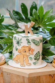 a lion cake sitting on top of a wooden table next to plants and other decorations