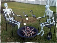 two skeletons sitting in lawn chairs next to a fire pit filled with marshmallows