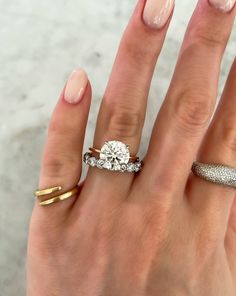 a woman's hand with two rings on it and a diamond ring in the middle