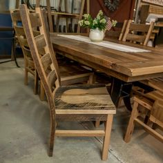 a wooden table with chairs and a vase filled with flowers sitting on top of it