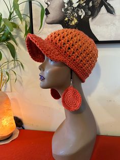 a mannequin head wearing an orange crochet hat and earring set