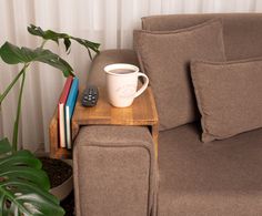 a coffee cup sitting on top of a wooden table next to a couch with books