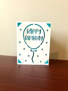 a birthday card with the words happy birthday on it sitting on a wooden table in front of a wall