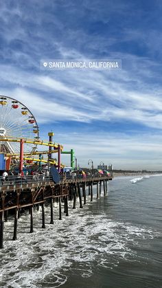 a ferris wheel sitting on top of a wooden pier next to the ocean in santa monica, california