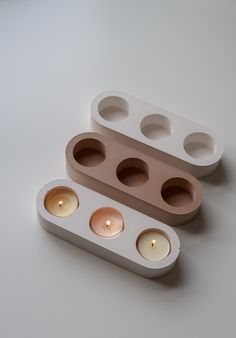 three candles are placed in the shape of an egg carton on a white surface