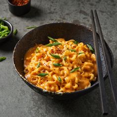 a bowl filled with macaroni and cheese next to chopsticks on a table