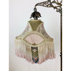 a lamp that is hanging from a light fixture with tassels and beads on it