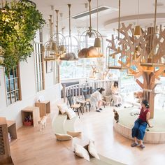 a woman sitting on a bench in a room with lots of furniture and hanging lights