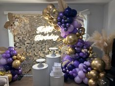 purple and gold balloons are on display in a room with other decorations, such as a balloon arch