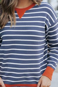 Upgrade your fall wardrobe with our Navy Stripe Contrast Sweater! This stylish and versatile piece features a subtle orange contrast detail at the neckline and cuffs, adding a pop of color to your outfit. Made with a comfortable crew neckline, stay cozy and chic all season long. Style with your favorite denim jeans, sneakers, and simple accessories for a chic everyday outfit. Fall Sweater With Striped Hem And Long Sleeves, Casual Fall Sweater With Striped Cuffs, Orange Color Block Crew Neck Sweater, Cotton Sweater With Striped Hem For Fall, Casual Tops With Striped Cuffs For Fall, Casual Sweater With Contrast Trim For Fall, Casual Fall Sweater With Contrast Trim, Fall Long Sleeve Sweater With Contrast Trim, Fall Workwear Sweater With Striped Hem