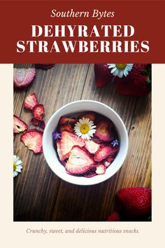 a bowl filled with strawberries sitting on top of a wooden table next to flowers