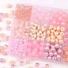 there are many different beads in the plastic container on the white table and one is pink