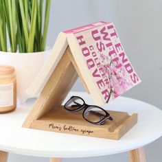 a pair of glasses sitting on top of a wooden stand next to a potted plant