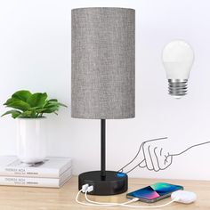 a table with a lamp, cell phone and other items on it next to a plant