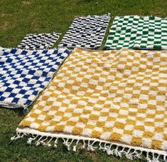 four different colored rugs laying on the grass