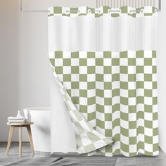 a green and white checkered shower curtain next to a toilet in a room with wood flooring